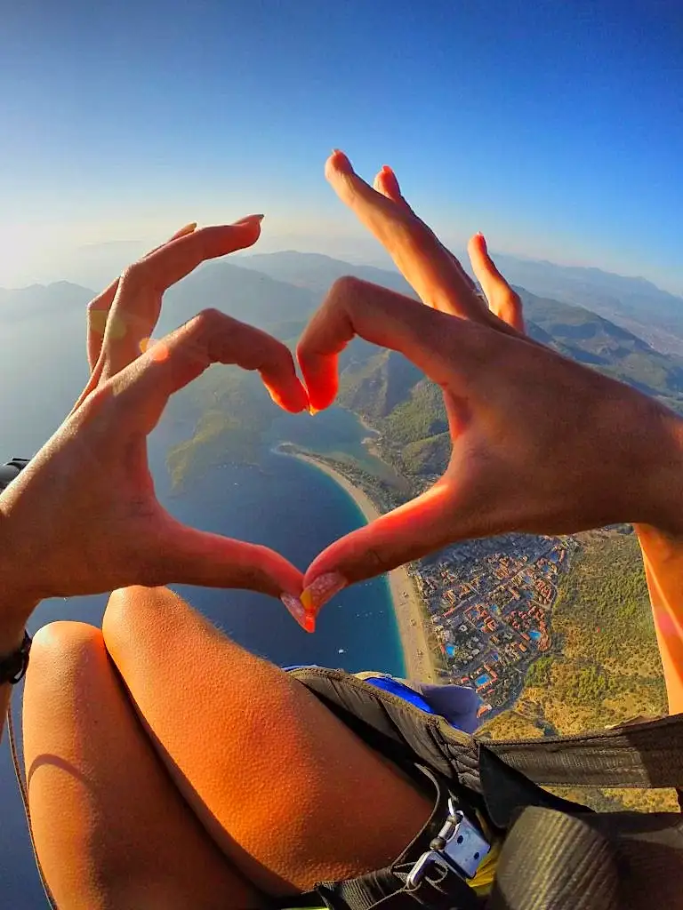 G0040850 A paragliding passenger creating a heart shape above the stunning blue lagoon, capturing the romance and beauty of Oludeniz